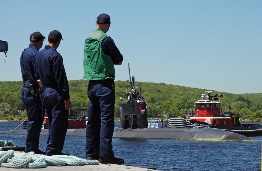 Buque de la Armada de Estados Unidos navegando, escoltado por embarcaciones