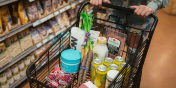 Persona empuja un carrito lleno de alimentos en un supermercado