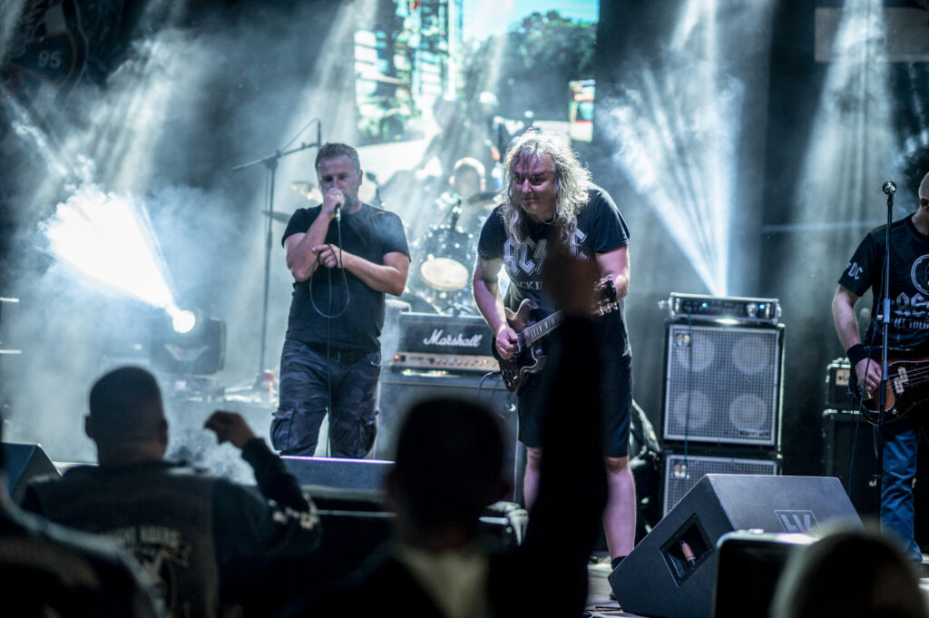 Banda en un concierto al aire libre con luces y público entusiasta de noche