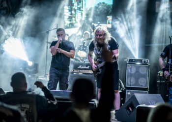 Banda en un concierto al aire libre con luces y público entusiasta de noche