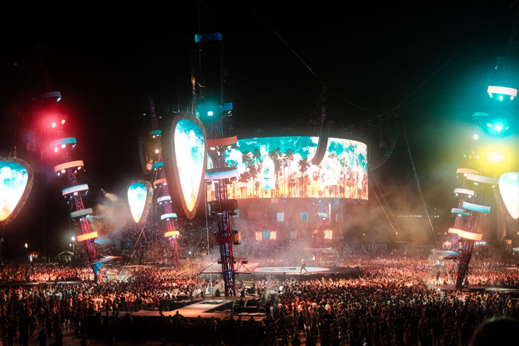 Gran público disfruta de un concierto de música con luces de colores en el escenario