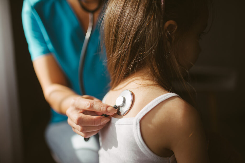 Una doctora ausculta a un paciente con un estetoscopio, relacionado con el acceso a la salud