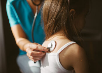 Una doctora ausculta a un paciente con un estetoscopio, relacionado con el acceso a la salud