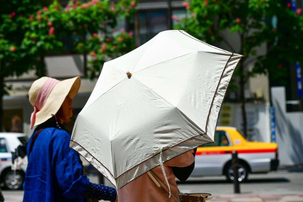 Personas se protegen del intenso sol de verano con sombrilla durante una ola de calor