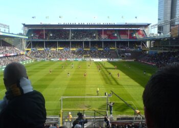 Jugadores disputan un partido de fútbol en un estadio lleno de aficionados
