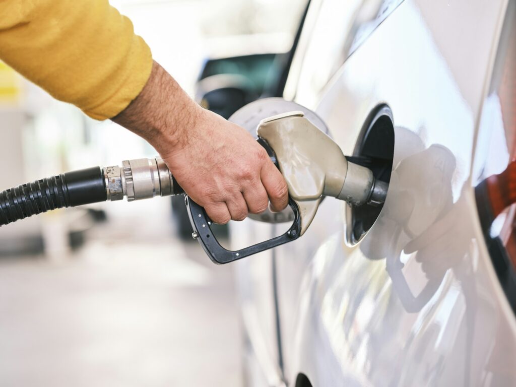 Una persona carga gasolina en su automóvil en una estación de servicio