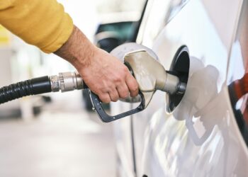 Una persona carga gasolina en su automóvil en una estación de servicio