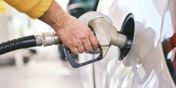 Una persona carga gasolina en su automóvil en una estación de servicio