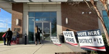 Una persona ingresa a un centro de votación junto a una urna electoral