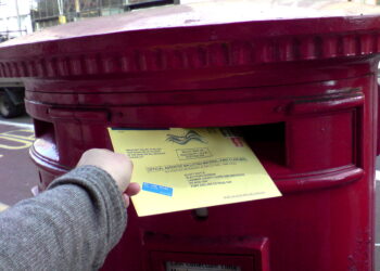 Una boleta electoral siendo depositada en una urna de votación