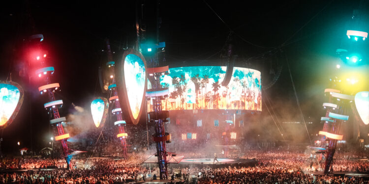 Gran multitud disfruta de un concierto con luces de colores en el escenario
