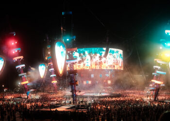 Gran público disfruta de un concierto iluminado por luces de colores frente al escenario