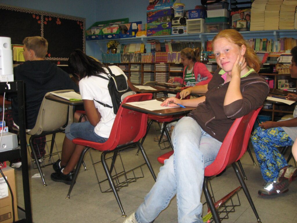 Ninos sentados en pupitres dentro de un salon de clases