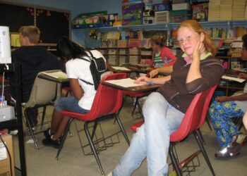 Ninos sentados en pupitres dentro de un salon de clases
