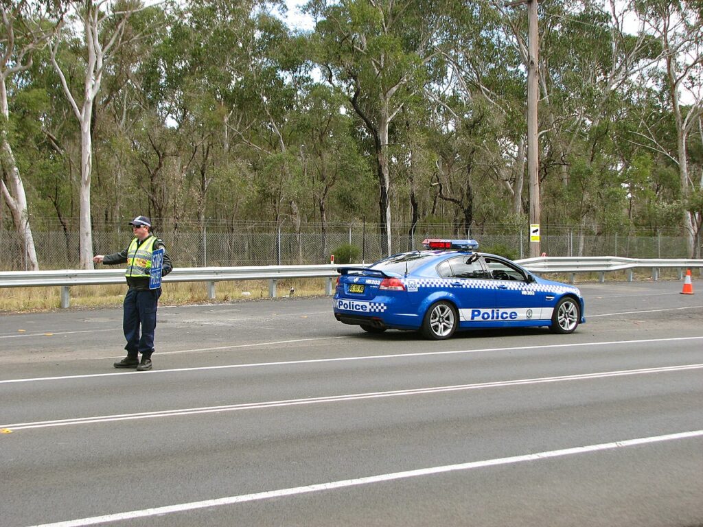 Un oficial de policía indica a un vehículo detenerse en una parada de tránsito en una carretera