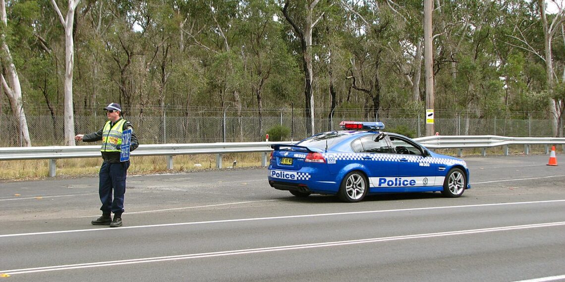 Un oficial de policía indica a un vehículo detenerse en una parada de tránsito en una carretera