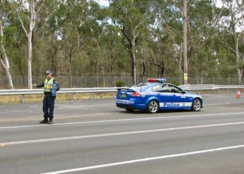 Un oficial de policía indica a un vehículo detenerse en una parada de tránsito en una carretera