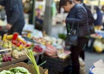 Personas compran frutas y verduras frescas en un mercado al aire libre