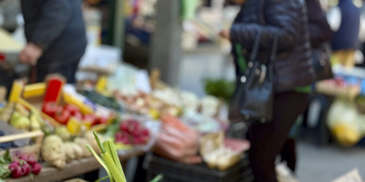 Personas compran frutas y verduras frescas en un mercado al aire libre