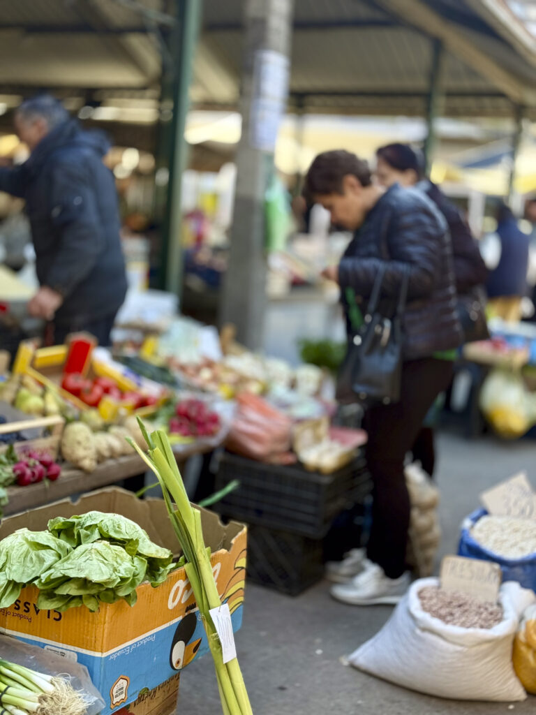 Personas compran frutas y verduras frescas en un mercado al aire libre