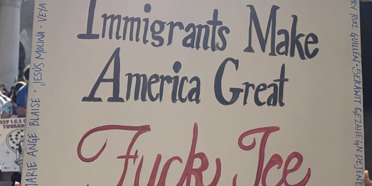 Manifestante sostiene un cartel en una protesta a favor de los inmigrantes y contra ICE
