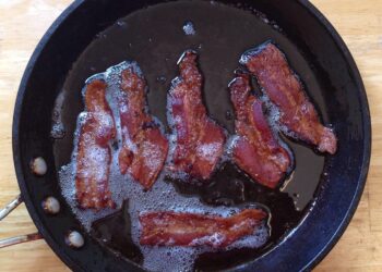 Tiras de tocino cocinándose en una sartén