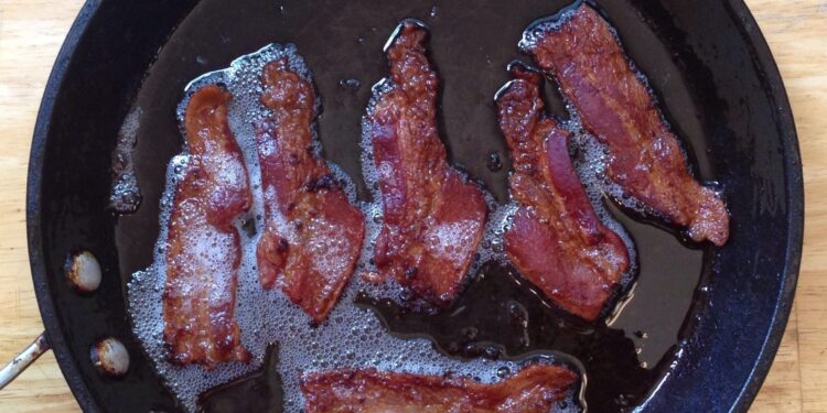 Tiras de tocino cocinándose en una sartén