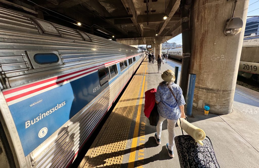 Pasajero se prepara para abordar un tren de pasajeros de Amtrak en una estación