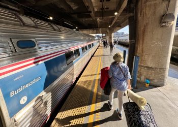 Pasajero se prepara para abordar un tren de pasajeros de Amtrak en una estación