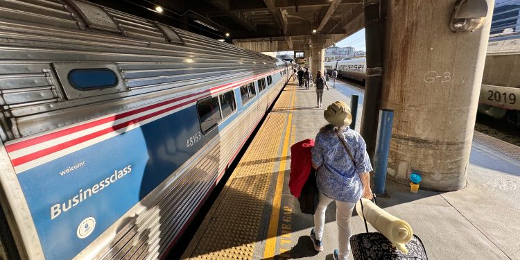 Pasajero se prepara para abordar un tren de pasajeros de Amtrak en una estación
