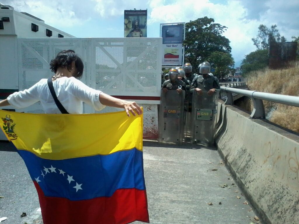 Persona con la bandera de Venezuela durante una manifestación