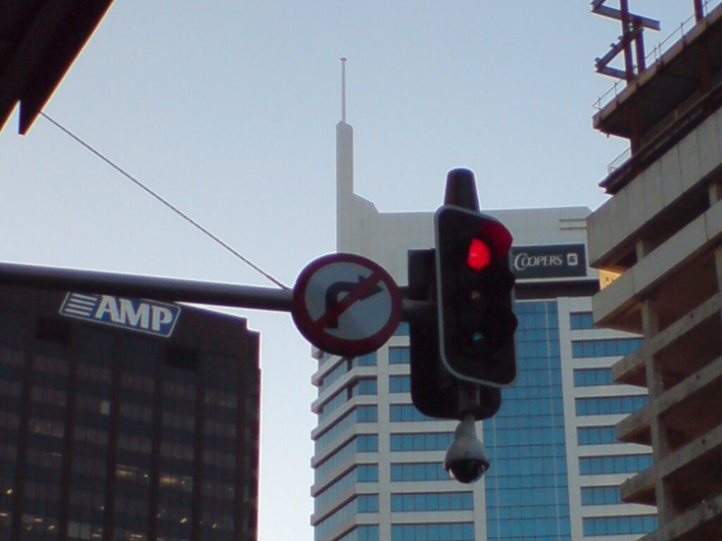 Poste con semáforos y una cámara de vigilancia sobre una calle