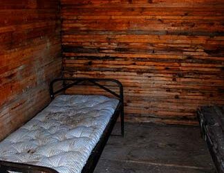 Interior de una celda de cárcel con una cama de metal