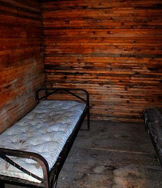 Interior de una celda de cárcel con una cama de metal