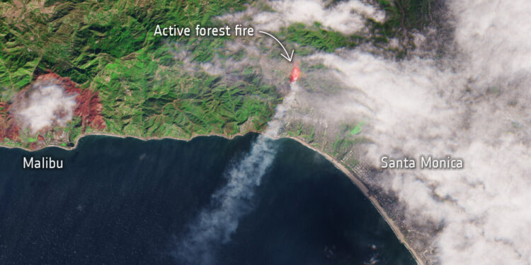 Llamas de un incendio forestal avanzando sobre una ladera cerca de casas