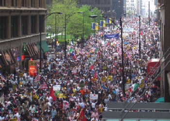 Multitud en una marcha por los derechos de los inmigrantes con banderas y pancartas