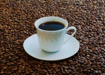 Una taza de café rodeada de granos de café tostado