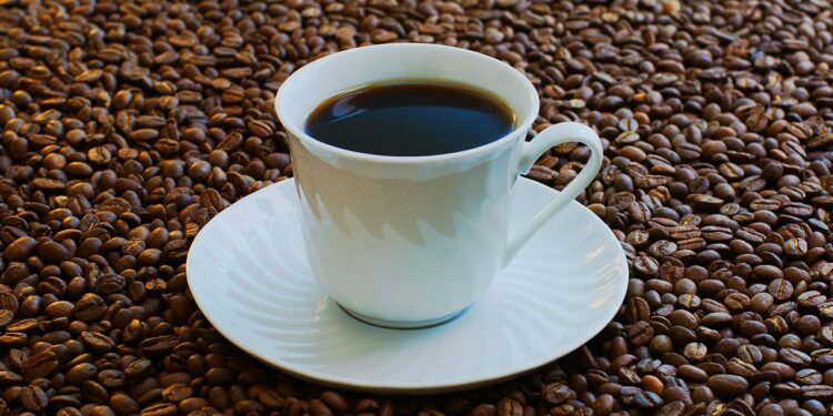 Una taza de café rodeada de granos de café tostado