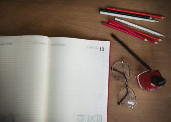 Cuadernos, lápices de colores y otros útiles escolares sobre un escritorio de madera