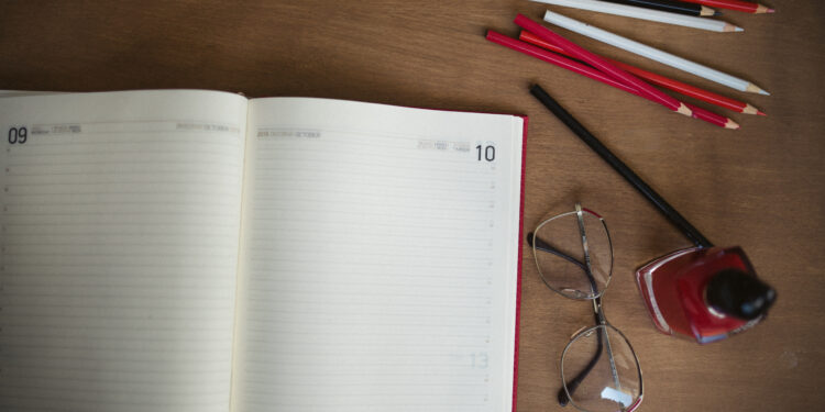 Cuadernos, lápices de colores y otros útiles escolares sobre un escritorio de madera