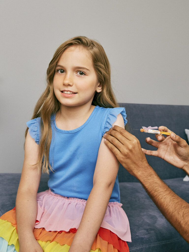 Una niña está por recibir una vacuna en el brazo