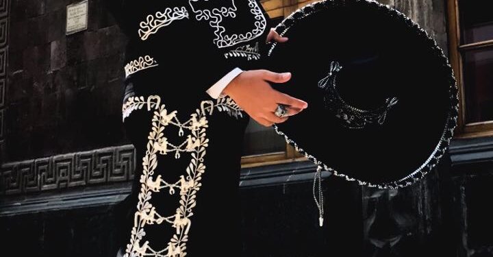 Integrantes de un mariachi con trajes tradicionales tocando música mexicana