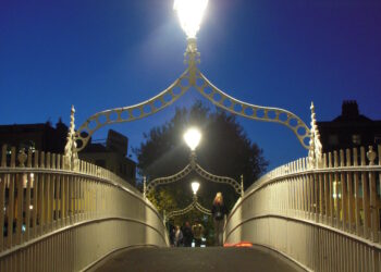 Puente Ha'penny iluminado al atardecer sobre el río Liffey en Dublín, Irlanda