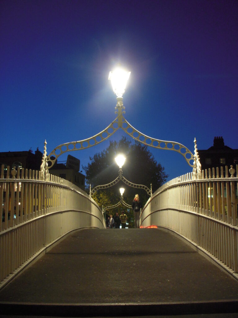 Puente Ha'penny iluminado al atardecer sobre el río Liffey en Dublín, Irlanda