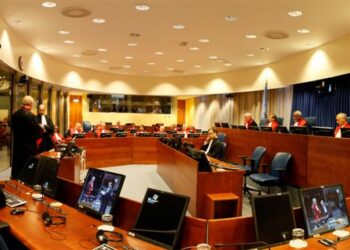 Interior de una sala de tribunal vacia con bancas y estrado del juez