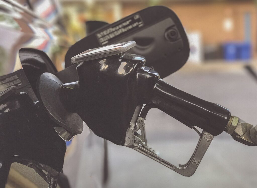 Persona sostiene la manija de un surtidor de gasolina para cargar combustible