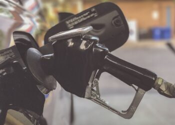 Persona sostiene la manija de un surtidor de gasolina para cargar combustible