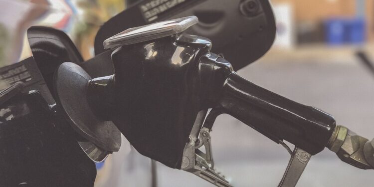 Persona sostiene la manija de un surtidor de gasolina para cargar combustible